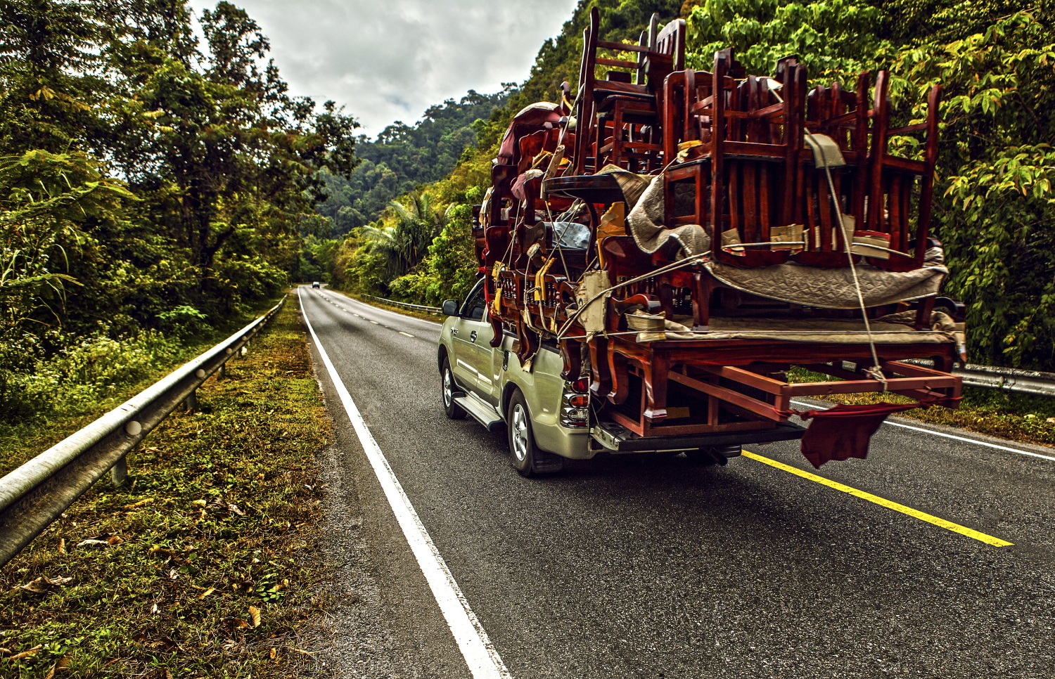 pickup overloaded with house utensils moves on the mountain road.